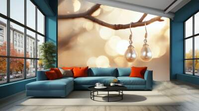 A pair of pearl drop earrings hanging delicately from a jewelry tree, set against a soft, glowing background. Wall mural