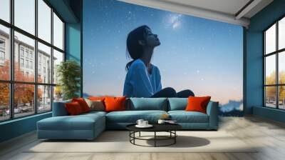 Serene Asian woman practicing mindfulness while observing the stars on a clear night, feeling connected to the universe. Wall mural