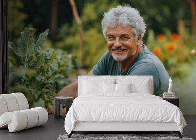 Smiling grey-haired man working in his garden, tending to plants and enjoying the outdoors. Wall mural