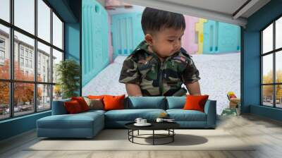 Cute little asian baby in Military uniform play toy Wall mural