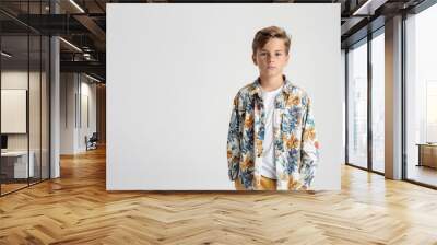 A young boy wearing a floral shirt, standing with a neutral expression against a plain background. His casual attire includes a white t-shirt underneath the colorful floral shirt. Wall mural