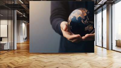 Person holding globe illuminated with city lights, symbolizing global connection and responsibility. warm lighting adds hopeful atmosphere Wall mural