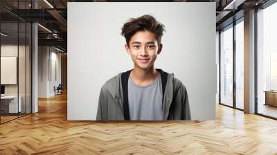 Portrait of a smiling young Asian man wearing a t-shirt with looking at the camera in confidently while standing alone in a grey wall background. Wall mural