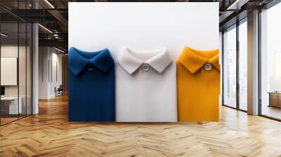 Stylish polo shirts in blue, white, and yellow colors are neatly arranged, showcasing their ribbed texture and classic collar design. Wall mural