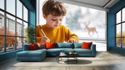 young boy in cozy yellow sweater is focused on drawing at table, with snowy window view and festive decorations in background, creating warm and cheerful atmosphere. Wall mural