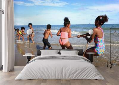 Children play tug of war game at beach, funny game on beach Wall mural