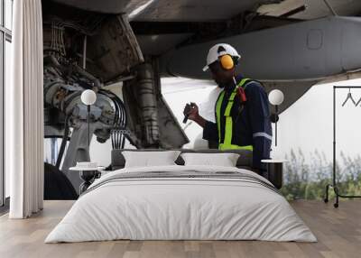 The black male aircraft mechanics use hand tools to work on inspection and do maintenance of an airplane, Aircraft technician examining a plane in the hangar Wall mural