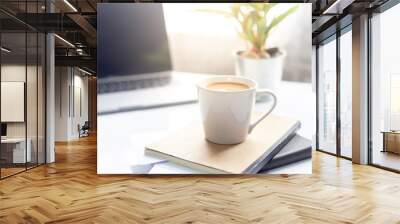 Coffee cup on notebook with laptop on white table in the morning sun light ,Working space Wall mural