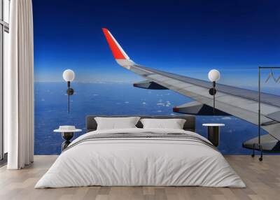 Wing of an airplane flying above the clouds Wall mural