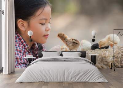 happy little girl with of small chickens sitting outdoor. portrait of an adorable little girl, preschool or school age, happy child holding a fluffy baby chicks with both hands and smiling.. Wall mural