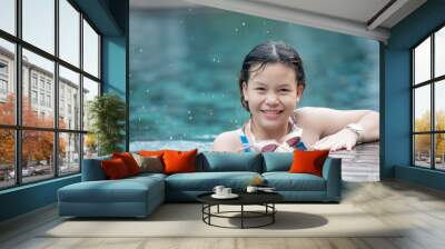 portrait of happy beautiful teen girl at the pool smiling at camera. teen girl surrounded by aqua pool water. child having fun in outdoor swimming pool. girl in summer vacation. Wall mural