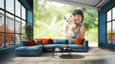 The girl stands carrying her puppy. Wall mural