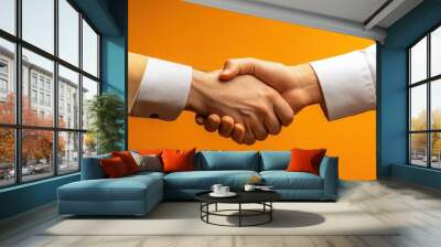 Close-up of a handshake over consulting documents, orange isolated background, studio lighting Wall mural