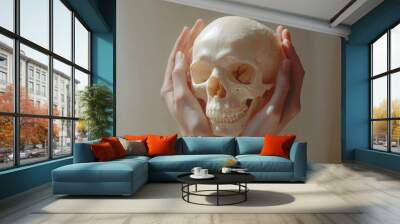 Two hands cradle a smooth skull from the sides, the bone glowing softly under even lighting on a minimal backdrop. Wall mural