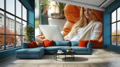 Woman balancing work on a laptop and tea in a comfortable chair, merging productivity and relaxation methods. Wall mural