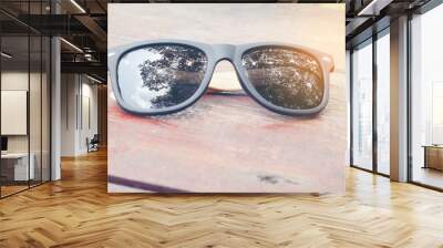 sunglass on wood background. reflection Shadow tree in lens. Wall mural