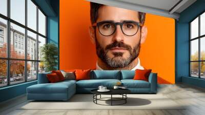 Stylish man in glasses against a vibrant orange backdrop Wall mural