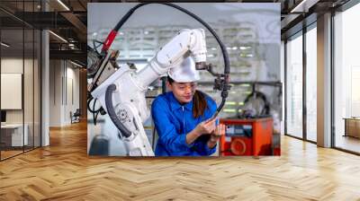 Asian factory worker woman hold tablet and maintenance with check part of robotic machine in workplace area. Industrial and technology support system help in working of employee concept. Wall mural