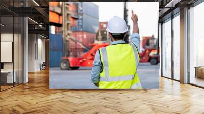 Back of foreman or cargo container worker show thumbs up to other co-worker who control crane truck in workplace area. Logistic and shipyard transportation for delivery system concept. Wall mural