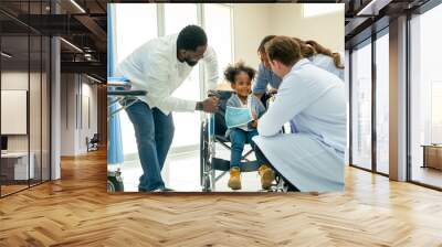 Doctor team help and take care child patient who injury with broken arm and sit on wheelchair and they look happy stay in emergency room. Wall mural