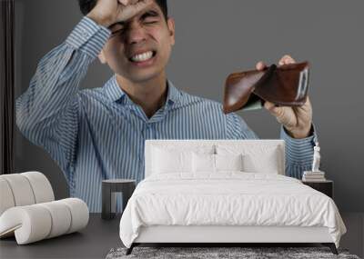 Portrait Handsome young asian man wearing a blue shirt stressed because empty wallet no money isolated on gray wall background. Businessman concept. Asia people. Wall mural