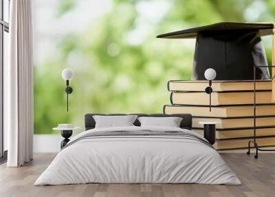 Graduation Cap on Books with Blurred Green Background Wall mural