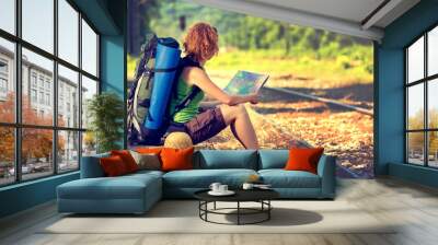 Girl wearing backpack and holding map, waiting for a train. Wall mural