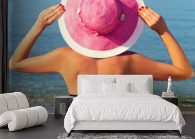 Young woman,holding pink hat,by the sea. Wall mural