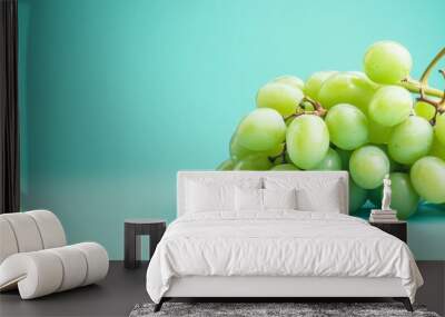 A bunch of fresh green grapes, arranged in a cluster, on a vibrant turquoise backdrop.  The image symbolizes freshness, health, abundance, and the beauty of simple nature. Wall mural