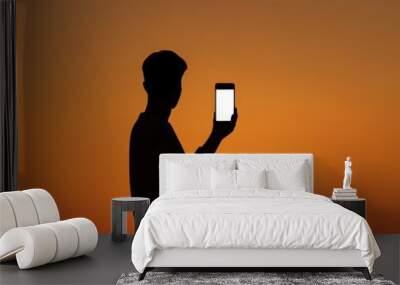 Silhouette of a person holding a phone with a bright screen against a vibrant sunset backdrop. The image symbolizes technology, communication, modern life, and the beauty of nature. Wall mural