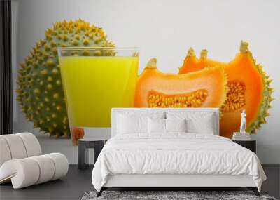 A glass of bright yellow horned melon juice sits alongside two slices of the fruit. The juice is a vibrant color, and the slices are fresh and ripe. The image symbolizes healthy hydration, natural swe Wall mural