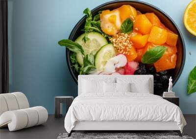 A top-down view of a colorful poke bowl with fresh ingredients, including salmon, cucumber, radish, watermelon, and black beans. The bowl is set on a light blue background with a few scattered sesame  Wall mural