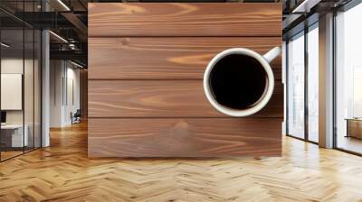 A top view of a white cup of coffee on a rustic wooden table.  The coffee is dark and rich, and the cup is set against the warm, natural wood. The scene evokes a sense of comfort, warmth, and relaxati Wall mural