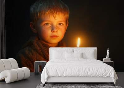 A young boy holds a lit candle in a dark room, symbolizing hope, light, innocence, faith, and perseverance. Wall mural