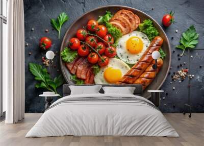 Delicious breakfast with fried eggs, grilled sausages, cheese, tomatoes, greens, and spices on plate on dark background Wall mural