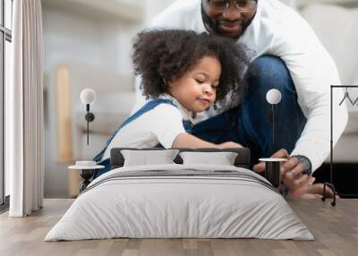 Cute little kid playing chess board toy as her parent sitting by. Multiracial family joyful game together with daughter child at home. Multiethnic girl enjoy playing chess pieces with her dad and mom. Wall mural