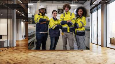 Group of factory workers wear safety uniform reflective jacket standing in plant floor. Diverse group of engineer people working together, portrait. Young adult men and women manufacturing teamwork. Wall mural