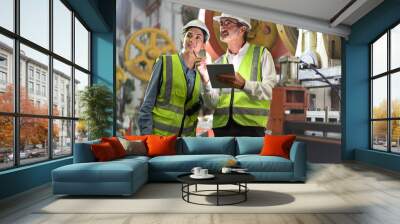 Senior manager train female technician to work in metalwork production factory. Industrial engineer man and woman standing in manufacturing facility talking machinery technology in heavy industry. Wall mural