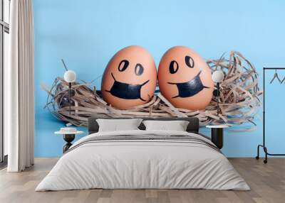 Egg couple in protective masks in nest isolated on blue empty space background. Covid-19 danger. Conceptual composition. Wall mural