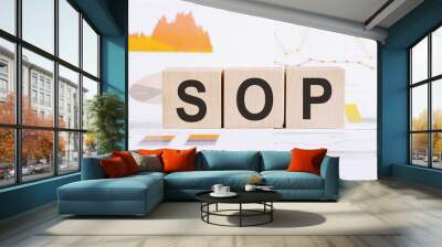 On a light background, graphs, diagrams and wooden cubes with the word SOP - standard operating procedure. Wall mural