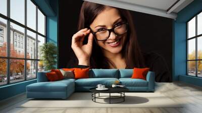 Beautiful thinking happy business woman  looking happy in eye glasses and holding spectacles in casual black t-shirt on black background with empty copy space. Closeup Wall mural