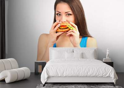 Thinking funny hungry excited woman eating burger and looking on blue background. Closeup Wall mural