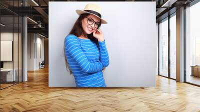 Thinking happy young woman in hat and glasses looking with smili Wall mural