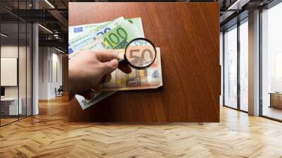 Finance saving, tax or searching for yield concept, magnifier glass on pile of Euro banknotes on wooden table, transparency of the European Union government economics idea. Wall mural