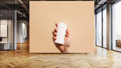 Hand holding antiperspirant, white deodorant on beige background, copy space Wall mural