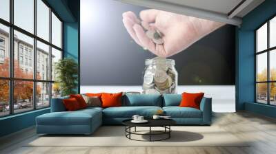 hand pours coins into the jar. the concept of saving and accumulating money Wall mural