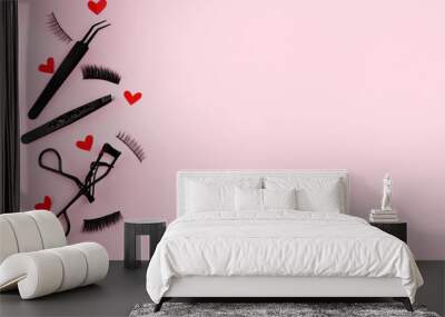 Lash curler, false lashes and tweezers for eye make-up on pink background with red hearts , copy space Wall mural