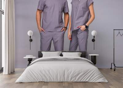 doctors relationship. male and female nurses in gray medical costumes are standing casual with smiles on the gray wall background, lifestyle medical concept, free space Wall mural