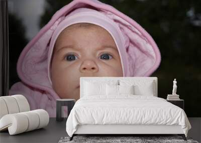 Newborn, baby, toddler or small child in a hoodie looking with interest at the camera with big blue eyes Wall mural