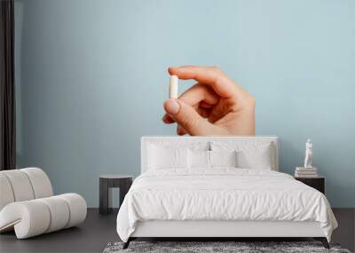 White pill in female hand on blue background, Taking Your Medication Wall mural